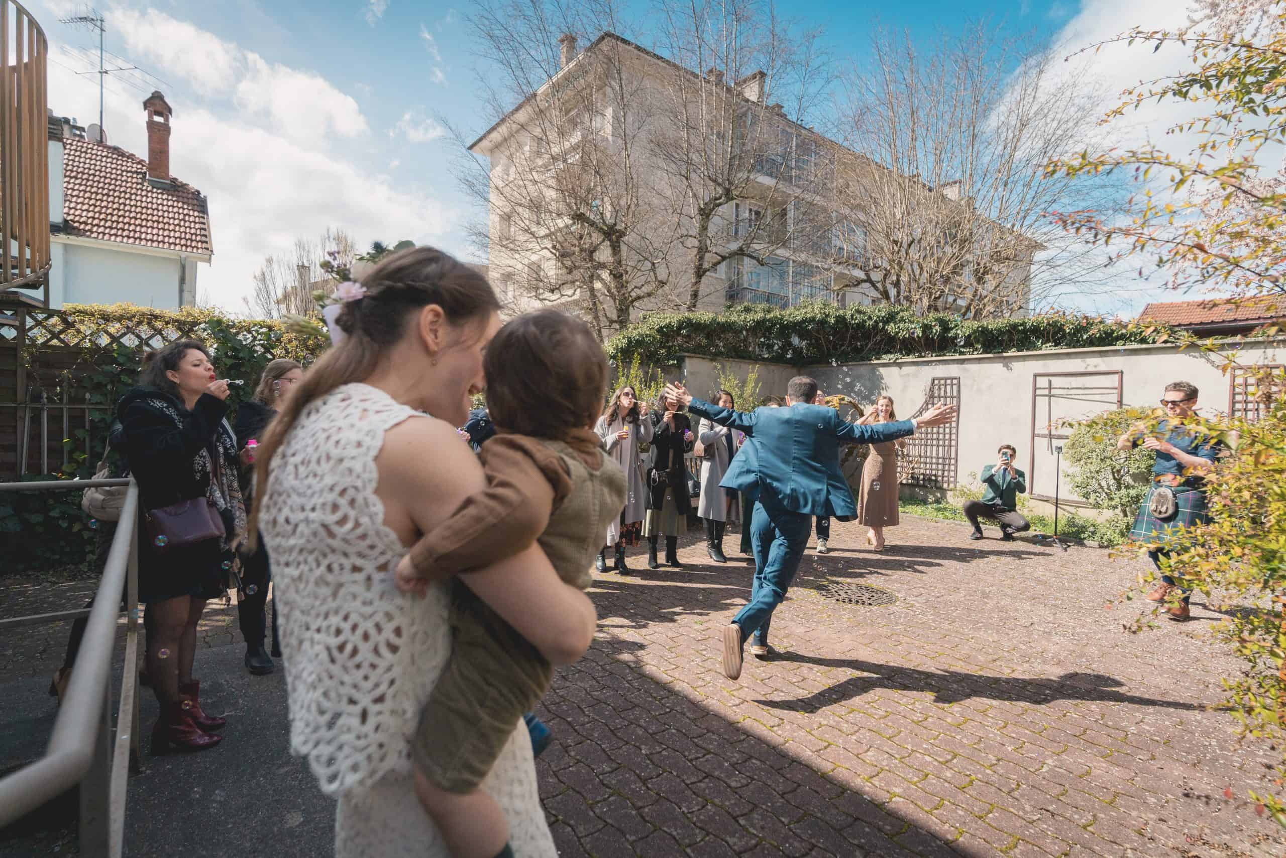 Photo de mariage en extérieur avec famille et amis lors d'une cérémonie joyeuse.