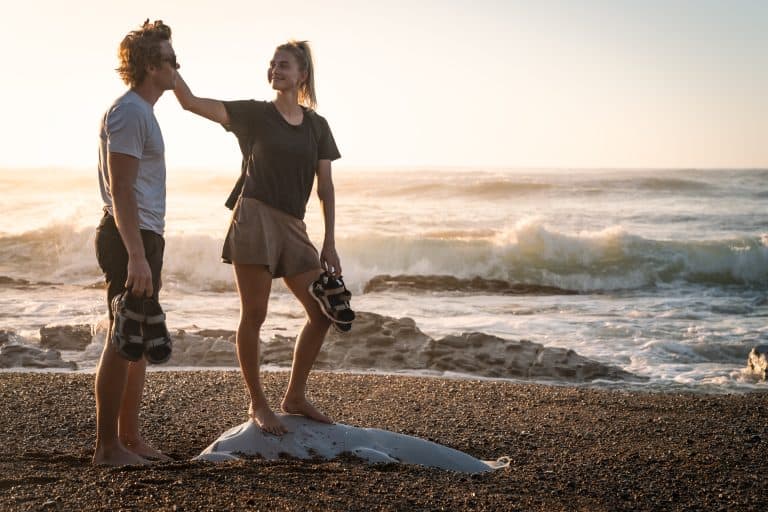 Baiser entre amis sur la plage au coucher du soleil, avec vue sur la mer et le sable.